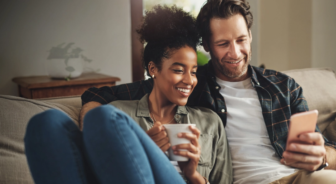 This is a picture of a couple looking at a phone together.